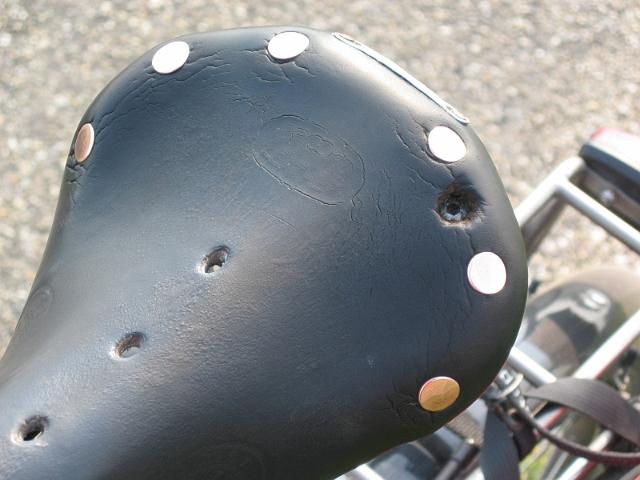 Zadel1.JPG - 25-06-2006
Tijdens de rustdag is er ook aan mijn fiets gesleuteld. Ik had problemen met mijn Brooks zadel, na 8 jaar en zo'n 35.000 km. Op de tweede fietsdag van de tocht is tijdens een klim op een zeer slechte weg één van de bouten, waarmee de veer aan de zadelbrug vastzat gebroken. Hierdoor was het zadeldek niet meer strak gespannen en zat ik in feite op het metaal van de zadelbrug, met wat rubber had ik het nog enigszins dragelijk gemaakt. Na al die dagen heel ongemakkelijk gefietst te hebben moest er toch wat gebeuren. Ik heb nog naar Nederland gebeld om evt. een zadel op te laten sturen via DHL, aangezien de Indische zadels niet passend waren te maken, maar dat opsturen bleek nogal lastig te zijn.
De juiste klinknagels waren in Kaza niet te krijgen en toen hebben we het maar anders opgelost. Met enige moeite, een scherp mes en een M6 bout met verzonken kop is het uiteindelijk toch gelukt om het zadel weer te maken. Ik heb er mijn reis in India mee gereden en het zadel zit nu nog steeds op mijn fiets. Met dank aan Gerard Murre en Eric Schuijt. De eerste heeft heel precies het gat in het zadeldek gemaakt en van de andere kwam het idee om het zo te doen (was het telefoontje naar de Vakantiefietser toch niet voor niks geweest).